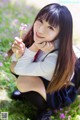 A young woman sitting in a field of flowers holding a flower.