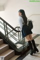 A woman in a school uniform is standing on the stairs.