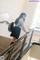 A woman in a school uniform is walking up some stairs.