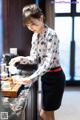 A woman pouring tea into a cup on a table.