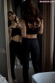 A woman standing in front of a mirror in a bathroom.