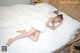 A woman laying on top of a bed covered in white sheets.