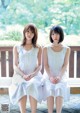 Two young women sitting on a wooden bench.