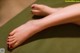 A woman's feet with red nail polish on a green mat.