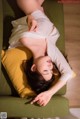 A woman laying on a green couch with her eyes closed.