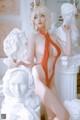 A woman in an orange bathing suit posing in front of a statue.