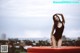 A woman in a black bathing suit sitting on a red mattress.