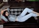 A woman laying on a black couch in a living room.