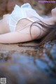 A woman laying on a rock in a white lingerie.