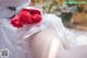 A woman in a wedding dress holding a bouquet of red roses.