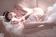 A woman in a pink lingerie laying on a white couch.