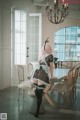 A woman in a maid outfit standing in front of a dining room table.