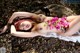 A naked woman laying on the ground with flowers in her hair.