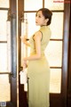 A woman in a green dress standing in front of a door.