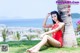 A woman in a red bathing suit sitting next to a palm tree.