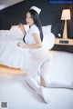 A woman in a white uniform is posing on a bed.