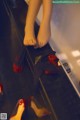 A woman's feet in a mirror with red shoes on the floor.