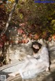 A woman in a white dress sitting on a stone wall.