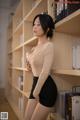 A woman standing in front of a bookshelf in a library.