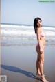 A woman in a pink bikini standing on a beach.