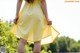 A woman in a yellow dress standing on a stone wall.