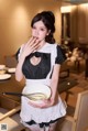 A woman in a maid outfit holding a bowl of food.