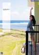 A woman standing on a balcony looking out at the ocean.