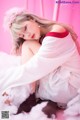 A woman in a pink dress sitting on a bed of fluffy white clouds.