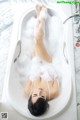 A woman laying in a bathtub covered in foam.