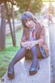 A woman in a school uniform sitting on a bench.