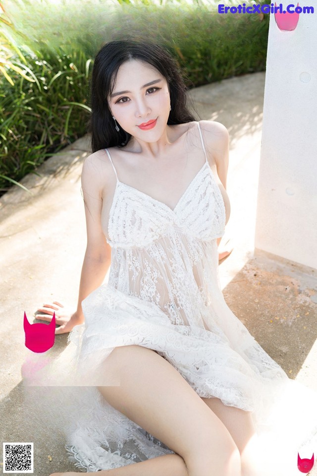 A woman in a white dress sitting on the ground.
