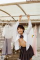 A young woman in a school uniform hanging on a clothes line.