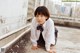 A young boy in a school uniform crouching down on the ground.