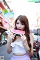 A woman holding a slice of watermelon in front of her face.