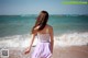 A woman in a purple dress walking on the beach.