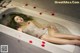 A woman laying in a bathtub covered in rose petals.