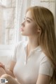 A woman sitting on a window sill looking out the window.