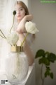 A woman sitting on a window sill next to a vase of flowers.