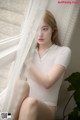 A woman sitting on a window sill next to a plant.