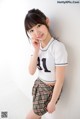A woman in a white shirt and plaid skirt posing for a picture.
