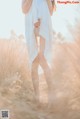 A woman in a white dress standing in a field.