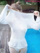 A woman in a white shirt is standing by a pool.