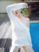 A woman in a white shirt is posing by a pool.