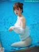 A woman in a white dress sitting in a pool.