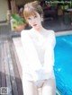 a woman in a white shirt is posing by a pool