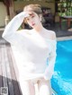 a woman in a white shirt standing next to a swimming pool