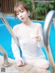 A woman in a white dress sitting by a swimming pool.