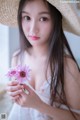 A woman in a straw hat holding a pink flower.