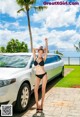 A woman in a black bikini standing next to a white car.