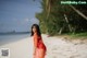 A woman in a red dress standing on a beach.